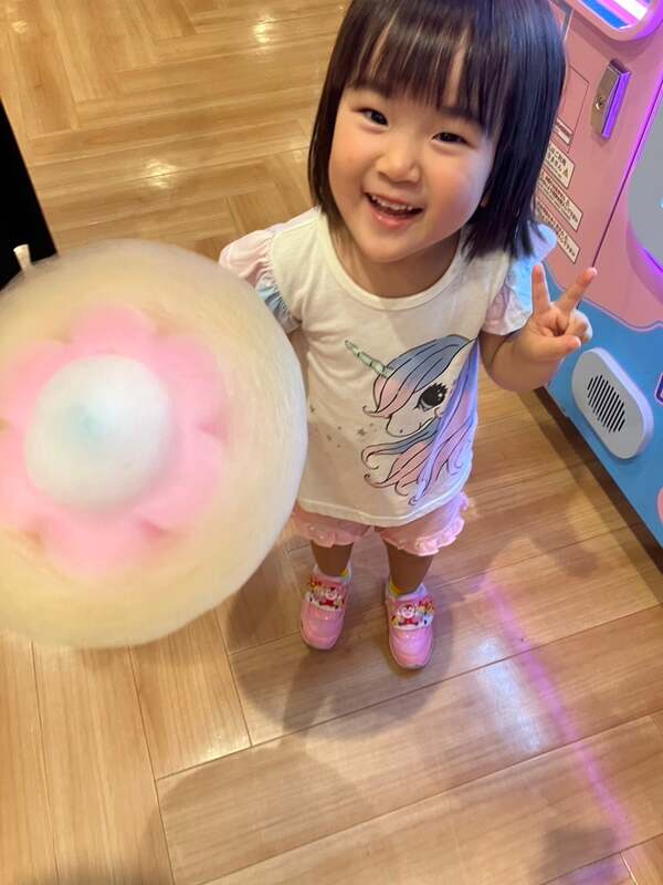 完成したわたあめを手に笑顔を見せる子供