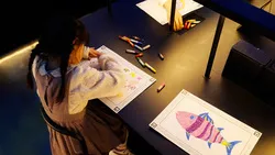 クレヨンを使って、紙に自由に魚の絵を描きます。チームラボ《スケッチオーシャン》（C） チームラボ